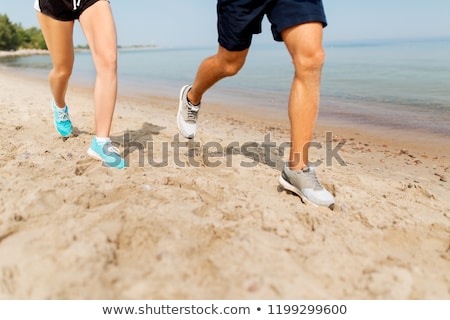 ストックフォト: Legs Of Sportsmen In Sneakers Running Along Beach