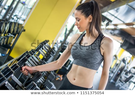 Foto stock: Young Woman Choosing Dumbbells In Gym