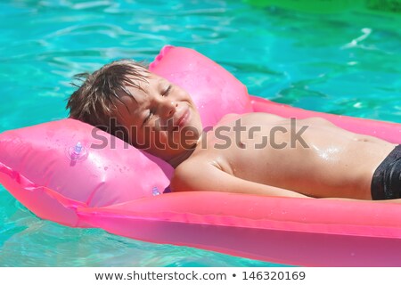 Stockfoto: Smiling Boy On Blue Inflatable Mattress In The Pool