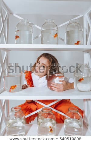 Сток-фото: Woman Looking Through The Closet With Gold Fishes In Jars