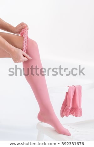 Foto d'archivio: Woman Putting On Stockings In Studio