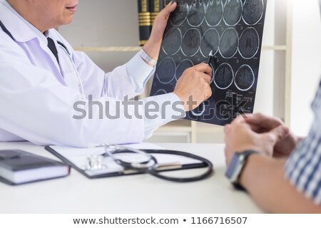 Foto stock: Doctor Analyzing A Scan Or X Ray Film Or Explains A Ct Scan Thou