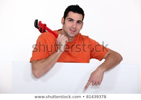 Foto stock: Craftsman Holding A Spanner And Pointing To A White Poster