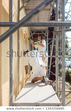 Foto d'archivio: Two Painters Working Diligently On Scaffold