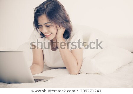 Stockfoto: Beautiful Blonde Using A Laptop On A Bed