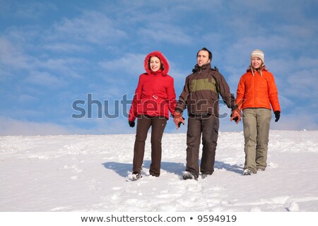 Foto stock: Three Friends Walk On Snow On Hillside 2