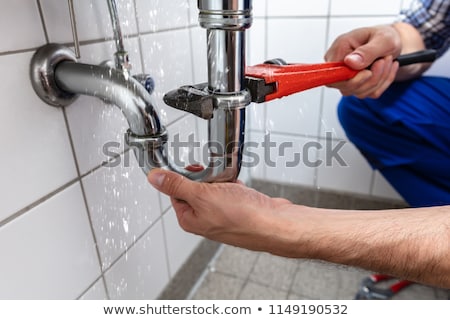 [[stock_photo]]: Plumber Fixing Sink Pipe With Adjustable Wrench