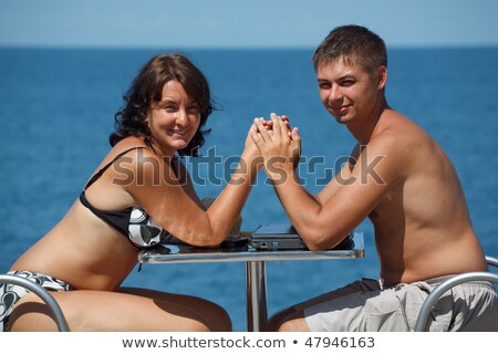 Stockfoto: An · en · vrouw · zitten · aan · tafel · onder · de · open · lucht · op · de · achtergrond · van · de · zee · en · hand · in · hand