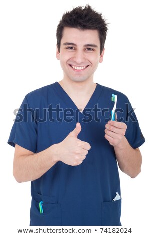 Foto stock: Smiling Young Nurse Holding Toothbrush And Showing Thumbs Up