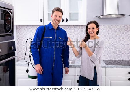 Foto stock: Smiling Woman Showing Thumbs Up Sign With Pest Control Worker