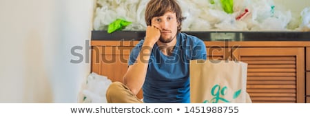 Foto stock: Man Holding A Package With The Inscription Go Green Amid A Pile Of Plastic Bags Zero Waste Concept