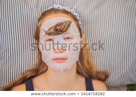 Stockfoto: A Young Woman Makes A Face Mask With Snail Mucus Snail Crawling On A Face Mask