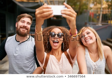 ストックフォト: Cheerful Friends Taking Photos Of Themselves On Smart Phone