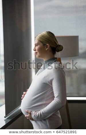 Foto stock: Pregnant Businesswoman Looking Through Window In Office