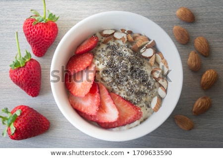 Stok fotoğraf: Homemade Oat Granola With Almond Nuts Slices Of Strawberries Seed Chia In A White Plate On A Gray