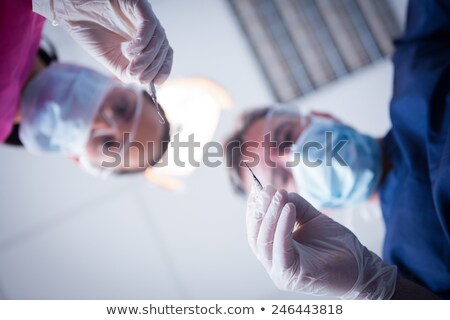 Stok fotoğraf: Dentist In Surgical Mask Holding Dental Tools Over Patient