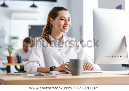 Stock photo: Happy Young Woman Dressed In Shirt Sitting At Her Workplace