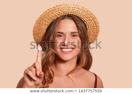 Foto stock: Young Woman Applying Sunscreen Lotion On Her Body At Beach