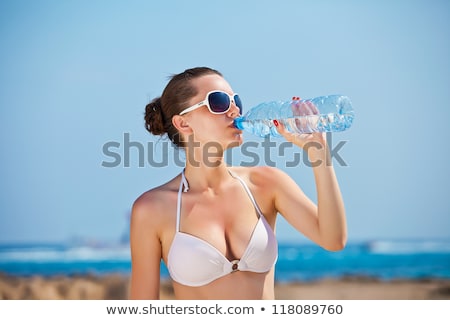 Foto d'archivio: Woman In Bikini With Bottle Of Drink On Beach