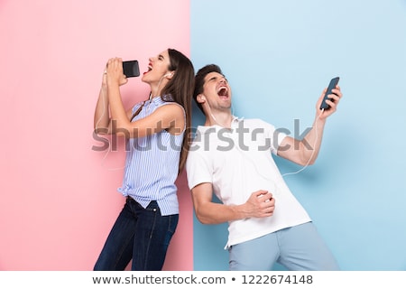 Foto stock: Image Of Cheerful Woman Wearing Earphones Singing While Holding