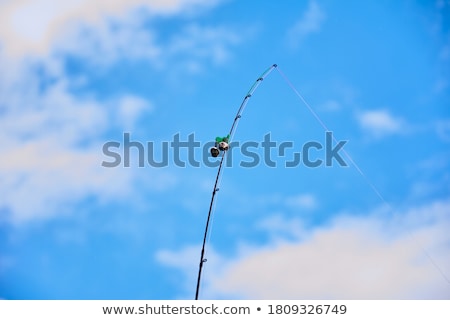 Stockfoto: Fishing Rod With A Bell On The Background Of Sky And Water