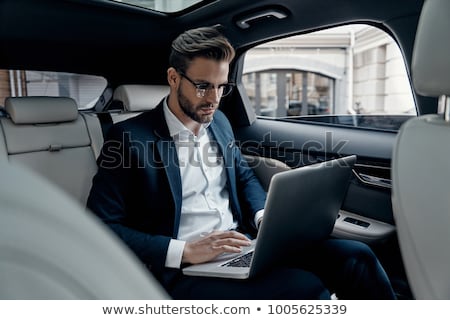 Stock photo: Handsome Young Businessman Using Laptop And Sitting In Back Seat