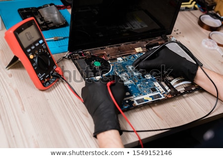 Stockfoto: Hands Of Contemporary Master Using Small Soldering Irons To Repair Broken Laptop