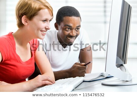 [[stock_photo]]: Two Female Students Working Together On Computer In Classroom