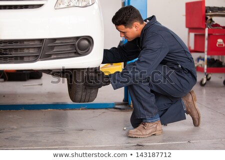 Foto stock: Mechanic Changing Tire From Suspended Car