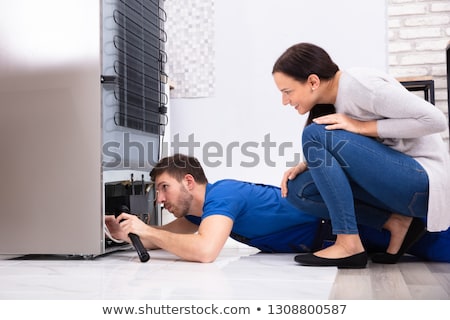 Foto stock: Technician Examining Refrigerator With Flashlight