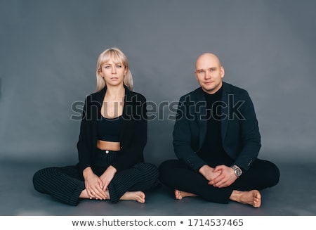 Foto stock: Portrait Of Young Beautiful Couple Sitting In Lotus Pose On Gree