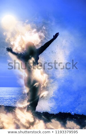 Foto stock: Silhouette Of Lone Woman Facing A Wave On Cliff Edge