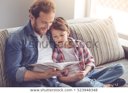 Foto stock: Happy Father And Son Reading Book Sofa At Home