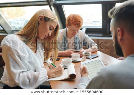[[stock_photo]]: Two Clever Guys Using Gadgets While Blonde Girl Making Notes In Notepad In Cafe