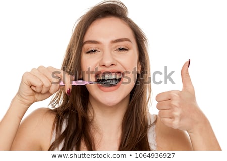 ストックフォト: Young Woman Brushing Her Teeth With A Black Tooth Paste With Active Charcoal And Black Tooth Brush