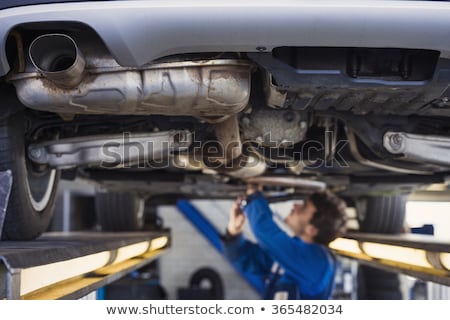 Foto stock: Exhaust Of A Car With Mechanic Underneath