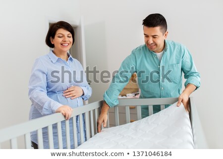 Stockfoto: Family Couple Arranging Baby Bed With Mattress