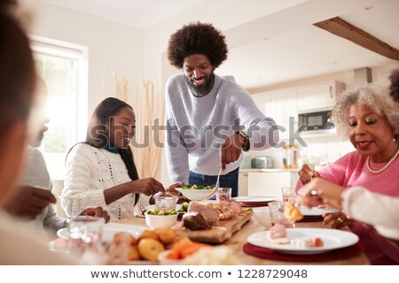 Stockfoto: Young Man And His Daughter Standing By Served Table In Front Of Rest Of Family