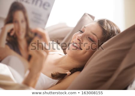 Foto stock: Young Woman Reading Magazine On Bed