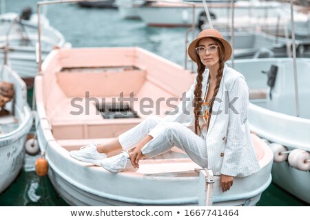 Stockfoto: A Young Girl In A White Suit Sits On The Stern Of A Pleasure Boat