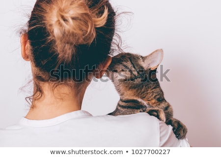 Foto d'archivio: Young Woman Holding Beautiful Tabby Cat Relaxed On Gray Backgro