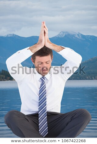 Stockfoto: Business Man Meditating Against Water And Mountains