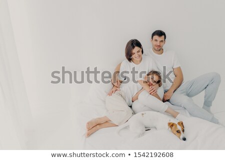 [[stock_photo]]: Happy Family Pose On White Bed During Weekend Father Mother Their Daughter And Dog Feel Comfort O