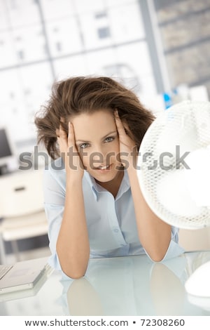 Foto stock: Woman Cooling Herself In Front Of Fan