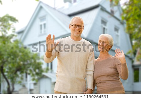 ストックフォト: Happy Senior Couple Waving Hands Over Living House