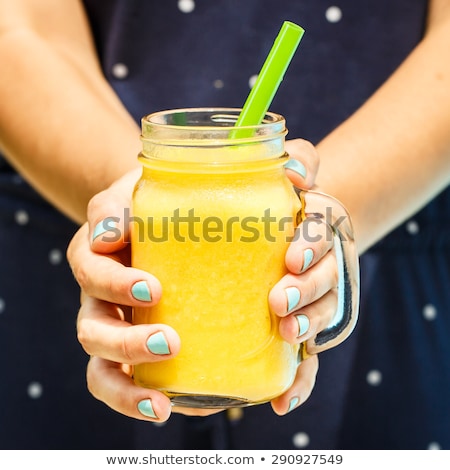 Foto stock: Young Woman Is Holding A Smoothie Of Mango On The Background Of The Pool Fruit Smoothie - Healthy E