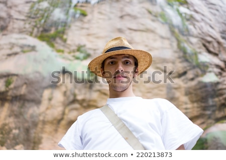 Foto stock: Young Man Enjoying In Natural Park At The Base Of Large Waterfal