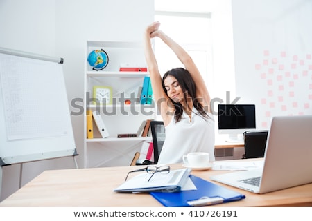 Foto stock: Businesswoman Sitting At The Table In Office And Stretching