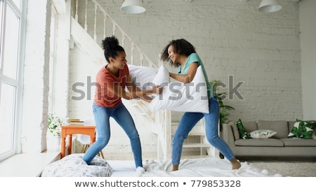 Foto stock: Happy Female Friends Having Pillow Fight At Home