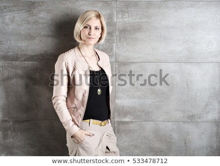 Stok fotoğraf: Woman In Leather Jacket Leaning With One Hand Against A Gray Stu